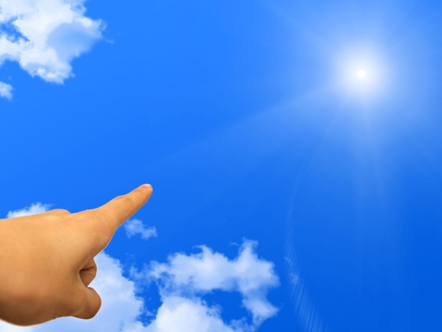 青空の太陽を指差す